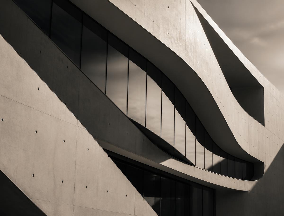 Abstract curved concrete and glass facade in strong diagonal light
